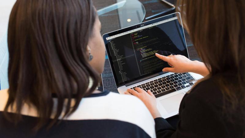 Two Women Looking at Code on a Laptop